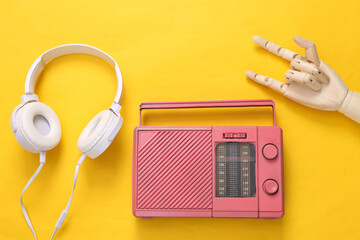 Stereo headphones and fm radio, wooden hand showing Rock gesture on yellow background. Top view....