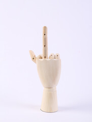 Wooden puppet hand shows indecent gesture, middle finger up on white background