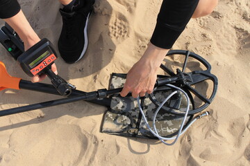 Assembling a metal detector on the sand of a beach.