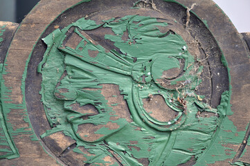 An old and weathered green colored wood carving in form of the face of a native american.