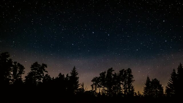 4k time lapse with starry sky and few clouds over forest.