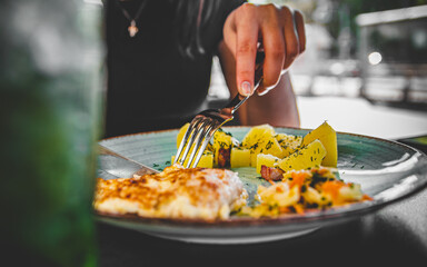 woman hand holding fork and knife eat chicken breast meat with potato in a plate 