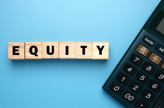 A picture of wooden block written Equity and calculator for financial equity concept. equity is ownership of assets that may have debts or other liabilities attached to them.