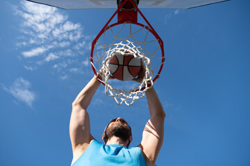 Close up image of professional basketball player making slam dunk during basketball game in outdoor...