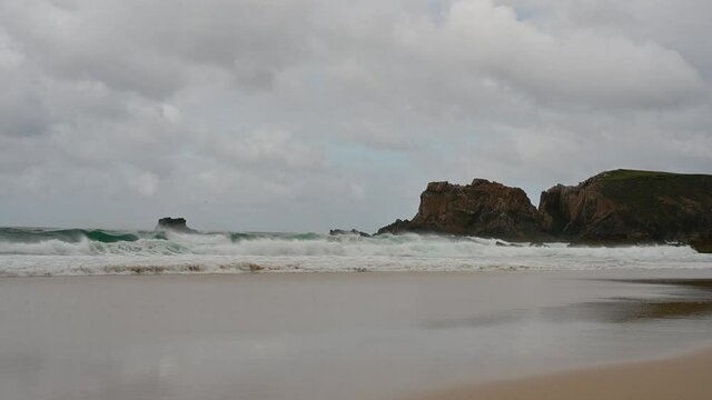 4k slow motion of waves crashing at Mangersta Beach, Isle of Lewis, Outer Hebrides, Scotland. Rocky cliffs, turquoise water, sandy beach. Cloudy day.
