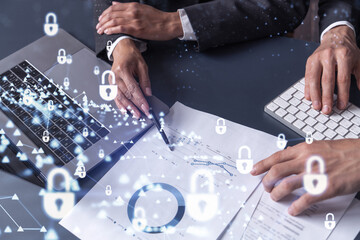 Two businesspeople man and woman working on the project to protect cyber security of international company. Padlock Hologram icons over the table with documents. Formal wear. Workspace.