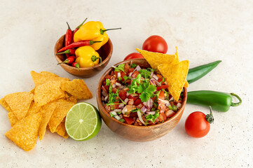 Mexican appetizer Pico de Gallo in a bowl and ingredients on the table.