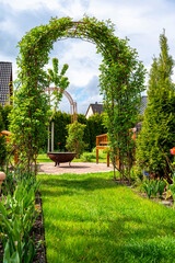 Traumhafter grüner Garten mit Rosenbogen und einer Feuerstelle als Dekorationsidee für das eigene Grundstück