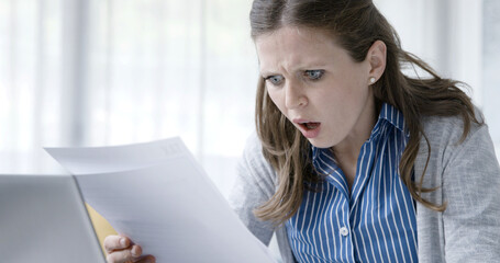 Disappointed woman reading a rejection letter - obrazy, fototapety, plakaty
