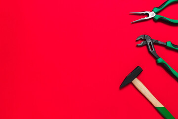 A set of quality green building tools to repair a car or a house on a red background. Do it yourself instruments. Banner for advertising construction shop with copy space. Business card
