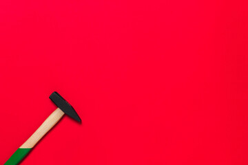 Hammer is isolated on a red background with place for text. Shop banner with construction tools. New Year or Christmas festive backdrop. One of the basic home use instrument for hammering nails
