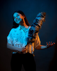 Girl in white shirt with dust brush on a dark background with colored light