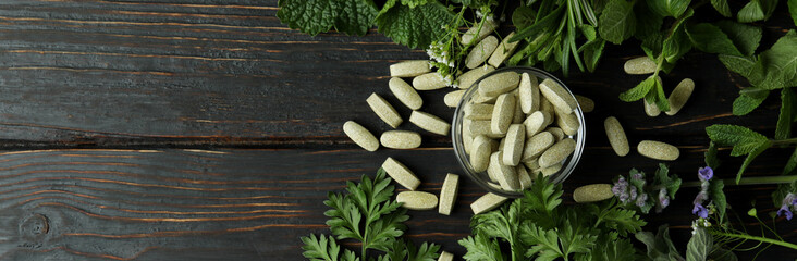 Concept of herbal medicine pills on wooden table, space for text