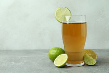 Glass of beer and limes against white textured background