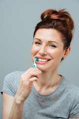 Woman with healthy white teeth holds a toothbrush and smiles. Oral hygiene concept