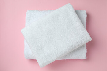 Clean folded towels on pink background, top view