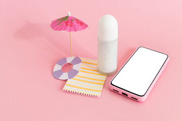 Assembling the skin care cream bottle container, beach umbrella and smart phone on pink background. Summer travel and vacation concept. Beauty and cosmetics concept.