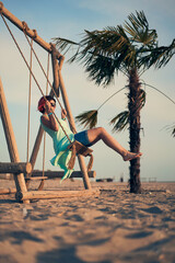 Young attractive woman with pink hair swinging on seesaw on the beach.