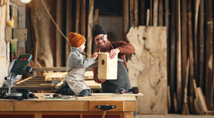 Kid with dad assembling wooden bird house in craft workshop