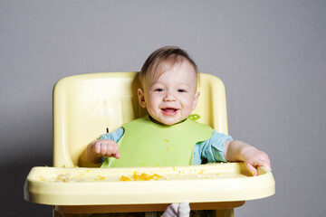 little child eats on gray background, child testing food, funny face