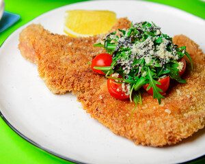 One deep fried fish bone steak with cherry tomatoes and fresh arugula on top.