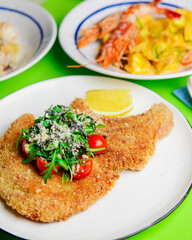 One deep fried fish bone steak with cherry tomatoes and fresh arugula on top.