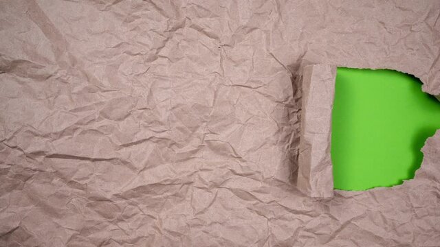 Stop Motion Video. crumpled brown paper ball unwrapping, then ripping open revealing green screen