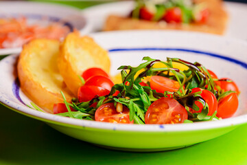 Baked camambert cheese with jam and fresh vegetable salad made from cherry tomatoes and green arugula