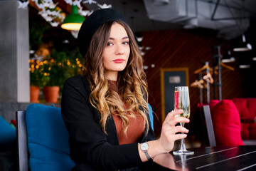Attractive young woman with a drink in restaurant. Caucasian woman sitting in restaurant and drinking champagne.