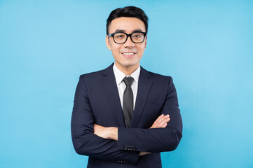 Portrait of Asian businessman with arms crossed and smiling on a blue background