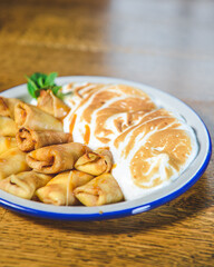 Close up of french style crepes with souffle whipped cream served on a plate over rustic wooden table background.