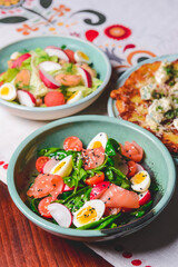 Salad with spinach, eggs and radish in a bowl, vegetable salad and potato pancake pizza.