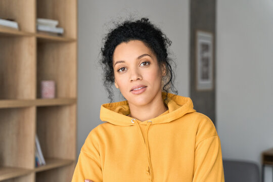 Headshot portrait of young attractive African American mixed race girl student in casual clothing hoodie posing indoors at modern living room home office looking at camera. Portrait - Powered by Adobe