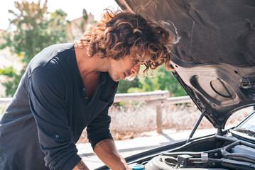 Young caucasian man trying to repair a breakdown in his car