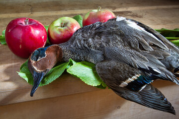 a shot duck and apples on a wooden table