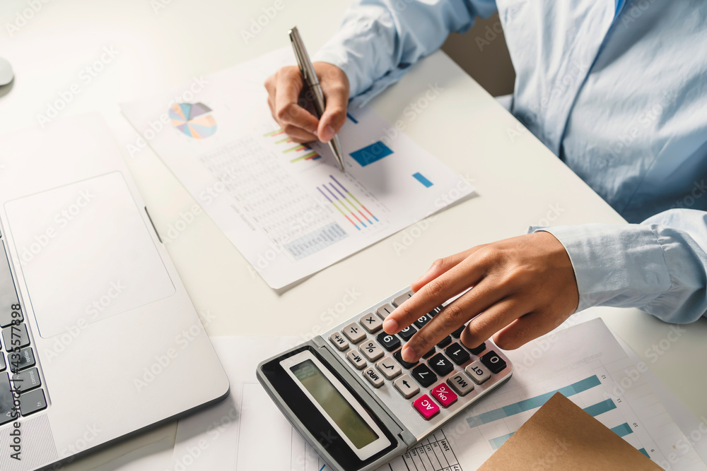 Wall mural woman accountant use calculator and computer with holding pen on desk in office. finance and account