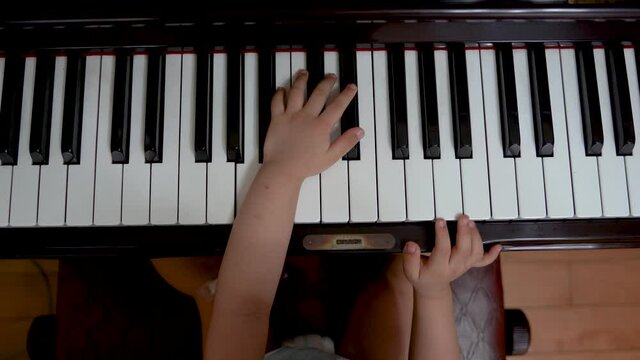 Toddler playing piano solo top view.