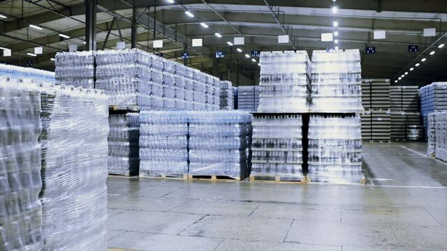 loader on the background of a huge industrial food warehouse with plastic PET bottles with beer,  water,  drinks.