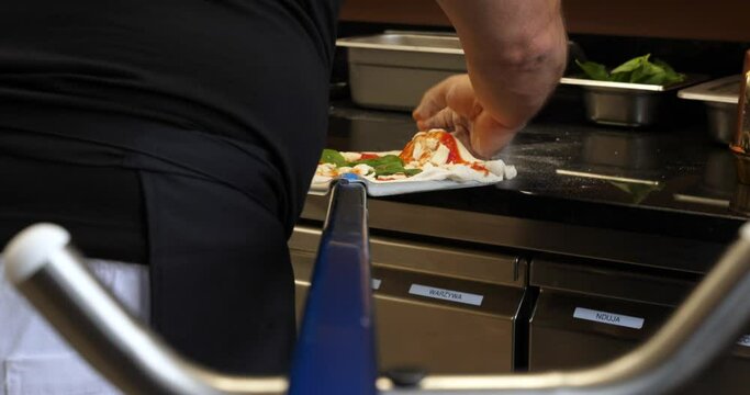 Chef arranging pizza on aluminum peel spatula