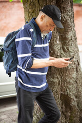 Latin American looking at the phone near a tree