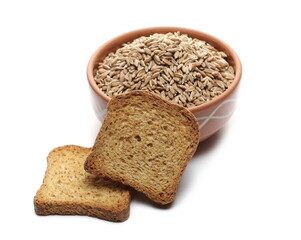 Spelt grains, seeds in clay bowl with bread slices, rusks isolated on white background