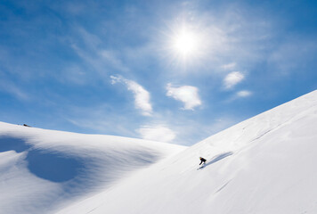 Skier rides on fresh snow against blue sky