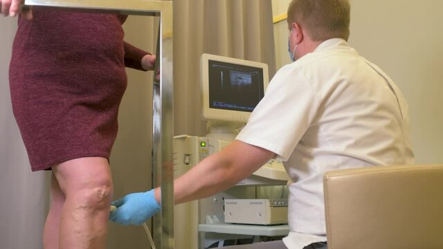 phlebologist or vascular surgeon examines the varicose veins of the lower extremities of a patient in a modern dermatological clinic.