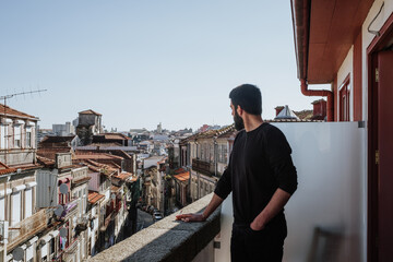 Young businessman looking at the city from his hotel balcony in Porto, Portugal