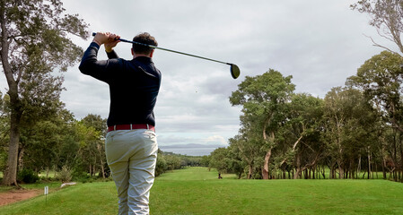 Golfer on the professional golf course. Golfer with golf club hitting the ball for the perfect shot.