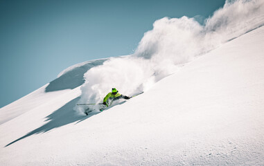 Skier rides in the mountain against the blue sky on fresh snow