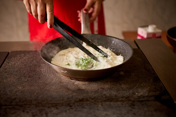 stirring green spinach in a skillet sauce for pasta