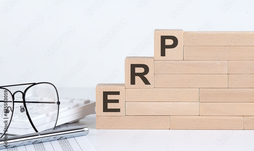 Poster three wooden cubes with letters erp on the white table with keyboard and glasses