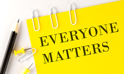 EVERYONE MATTERS word on the yellow paper with office tools on white background