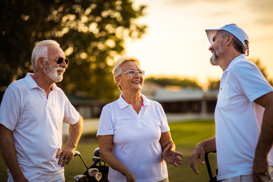 Three seniors golfers talking on golf field.
